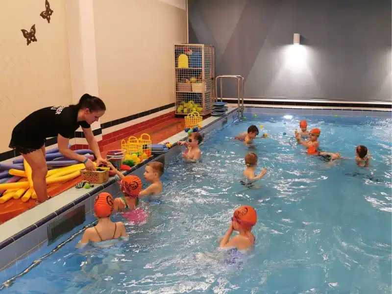 Swimming Coach giving swimming lessons by the pool.